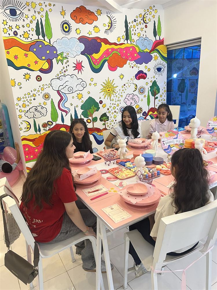 A table of crafters mid-workshop in front of the studio mural
